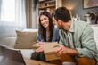 © Miljan Živković - Couple open birthday gift together via video call on tablet at home