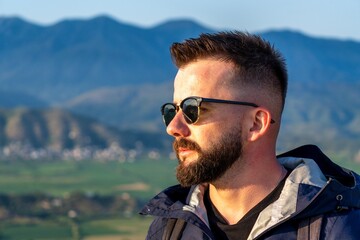 A handsome young Albanian man wearing sunglasses looking at a landscape of Albanian riviera in southern Albania. 