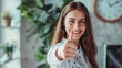 © venusvi - Happy female designer standing in office, giving a thumbs up and looking at the camera