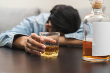 Health care alcoholism drunk, fatigue asian young man holding glass of whiskey, depressed male drink booze, sleep on table at home. Treatment of alcohol addiction, suffer abuse problem alcoholism.