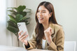 © KMPZZZ - Happy cheerful asian young woman celebrate online looking at smart phone on mobile app screen, receive good news, enjoying with great offer from social, hands expression, gesture successful at office.