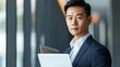 © GMeta - Confident Asian Male Business Executive in Business Suit Holding Laptop