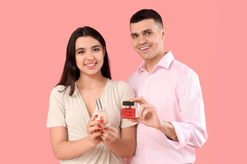 Poster - Young couple with bottles of perfume on pink background