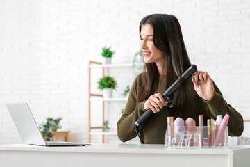 Canvas Print - Beautiful young happy female blogger with laptop and curling on recording video at home