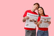 © Pixel-Shot - Young couple with newspapers on pink background