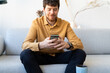 © Alba Vitta/Stocksy - man using phone at home