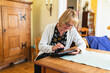© Diego Martin/Stocksy - Senior woman at home working on a digital tablet