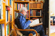 © Diego Martin/Stocksy - Senior retired man reading a book sitting in easy chair