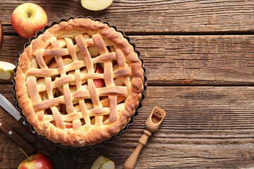 Wall Mural - Tasty homemade apple pie with fruits and cutlery on wooden background