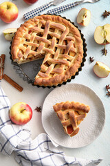 Wall Mural - Tasty homemade apple pie with fruits, cinnamon and cutlery on light blue background