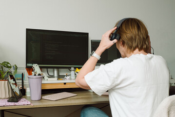 A young female programmer puts on headphones before starting work 