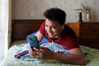 © Saptak Ganguly/Stocksy - Happy young man spending time leisurely with mobile phone