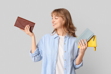 Sticker - Beautiful young woman holding wallets on grey background