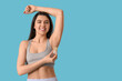 © Pixel-Shot - Happy smiling young woman using crystal deodorant on blue background