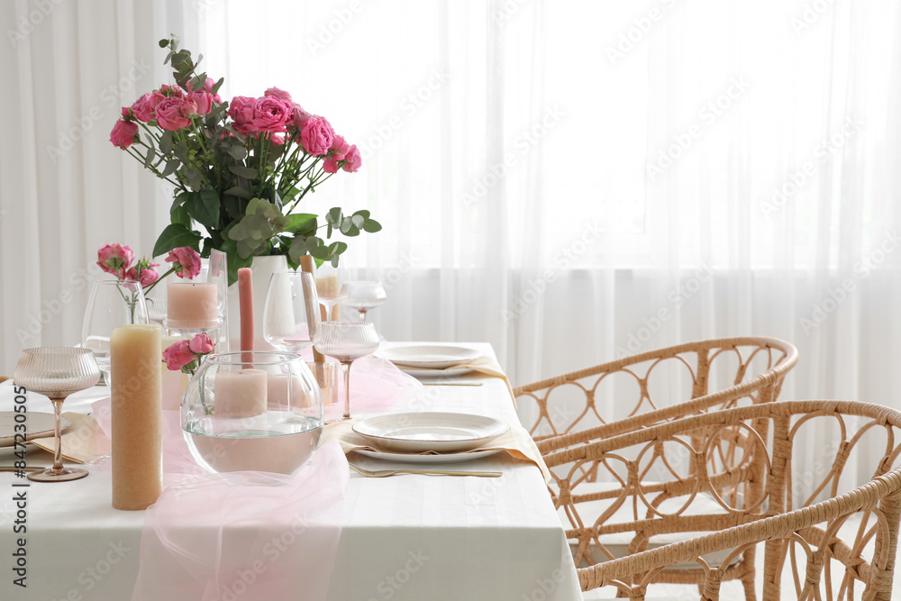 Beautiful table setting with pink roses and candles for wedding celebration in room