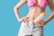 © Pixel-Shot - Young woman with sunscreen cream in shape of heart on her belly on blue background