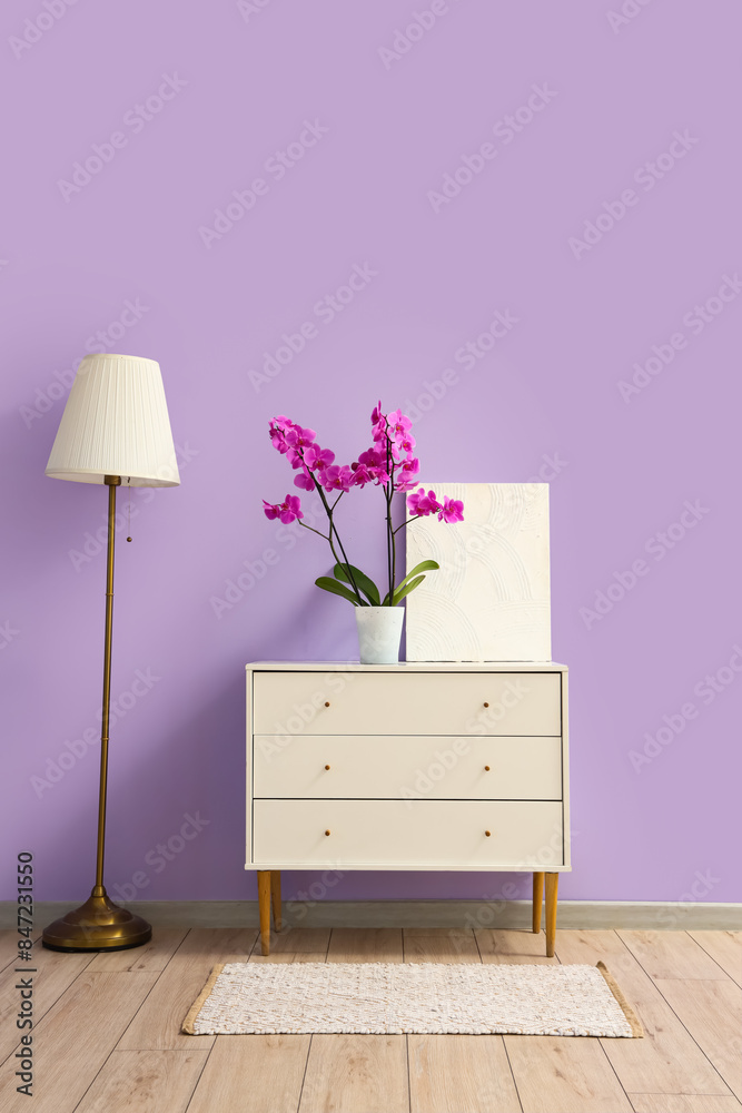 Interior of room with lamp and orchid flower on commode