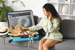 © Pixel-Shot - Beautiful young happy woman unpacking summer clothes from suitcase at home