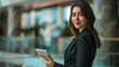 © ปฏิภาน ผดุงรัตน์ - Beautiful elegant business woman in dark business clothes holding tablet and looking at camera smiling inside office building created with