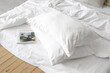 © Pixel-Shot - Stack of pillows and magazine on white bed, closeup