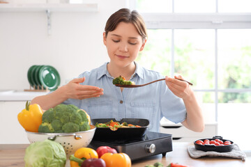 Poster - Young woman in wheelchair frying vegetables at home