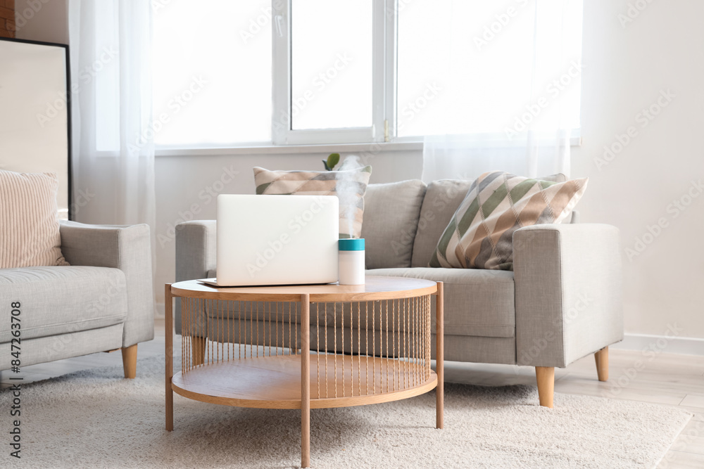 Air humidifier with laptop on coffee table in living room interior