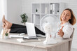 © Pixel-Shot - Beautiful mature happy businesswoman with laptop, glass of water and electric fan in office