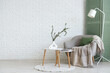 © Pixel-Shot - Cozy armchair and vase with eucalyptus branches on coffee table in living room
