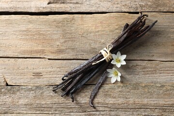 Wall Mural - Bunch of vanilla pods and flowers on wooden table, top view. Space for text