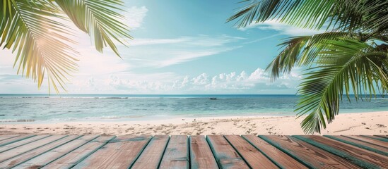 Wooden table and palm leaves on an empty beach, setting for a summer party.