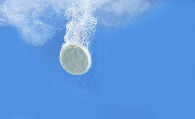 Wall Mural - Effervescent pill dissolving in water on blue background, closeup