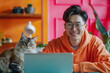 © Sage Studios - Happy Asian Man Working on Laptop with Cat in Bright and Colorful Home Office
