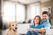 © BillionPhotos.com - happy couple sitting together on sofa with a dog