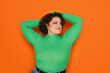 © VICTOR TORRES/Stocksy - Joyful curvy woman in green top on orange background