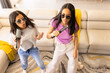 © Wavebreak Media - Two biracial young sisters singing into hairbrushes while wearing sunglasses, at home
