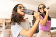© Wavebreak Media - Two biracial young sisters are singing into hairbrushes while wearing sunglasses, at home