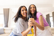 © Wavebreak Media - Two young biracial sisters enjoying karaoke together, smiling and holding microphone, at home