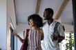© Wavebreak Media - A diverse couple is standing together, smiling and looking out window, vacation home