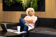 © Wavebreak Media - Young biracial woman on couch with laptop and coffee cup in modern business office