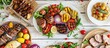 © Lasvu - Summer BBQ or picnic featuring grilled meats, vegetables, fruits, salads, and potatoes displayed on a table with a white wood backdrop from above.