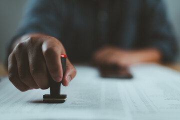 Poster - Closed up businessman hand using wooden stamping to document approve and reject document or project concept, copy space.