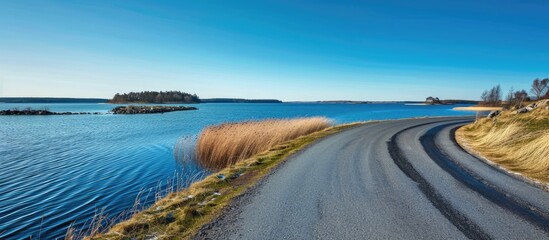 Canvas Print - Asphalt road encircling the lake beneath a clear blue sky.