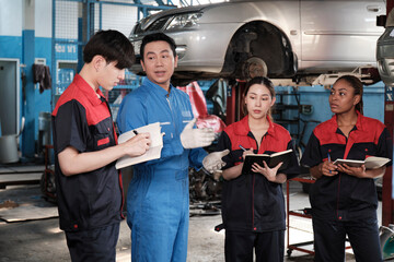 Specialist lecture. Male supervisor engineer describe automotive suspension fixing with mechanic worker staff teams for repair work at car service garage and maintenance jobs in automobile industry.