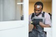 © Serhii - Young African Repairman In Overalls Installing Window