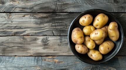 Wall Mural - Organic farm new potatoes arranged on a black clay dish with a backdrop of gray wooden surface