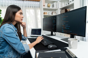 Wall Mural - Young Asian in IT developer creating with typing online information on pc with coding program data of website application, wearing jeans shirt. surrounded by safety analysis two screens. Stratagem.