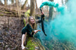 © ako-photography - Woman holding smoke bomb in forest. Shallow depth of feld