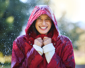 Outdoor, portrait and woman with raincoat for winter season and walking in park for relax. Female person, happy smile and rain jacket to shield for wet climate or water drops and fun in nature garden