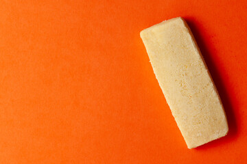 Wall Mural - On an orange background, one sweet and tasty coconut butter cookie. Top-down view. Food Flat lay.