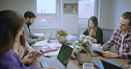 Wall Mural - Young employees collaborate in a startup office, brainstorming and discussing project ideas and strategies, fostering a dynamic and innovative environment.